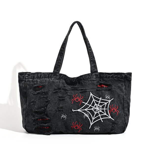 Large washed black distressed denim tote bag with white spider web embroidery and red spider motifs on the front panel