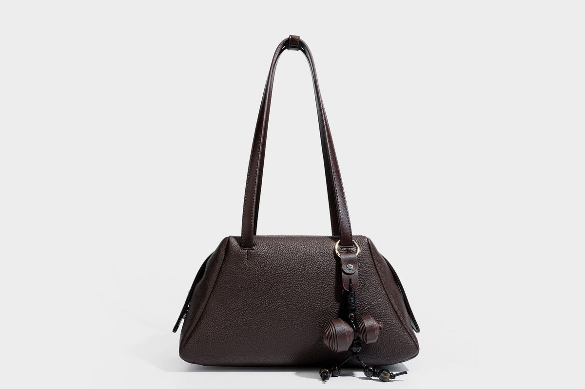 Structured trapezoid shoulder bag in dark brown pebbled leather-look finish with slim double straps, top zip closure, side