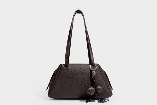 Structured trapezoid shoulder bag in dark brown pebbled leather-look finish with slim double straps, top zip closure, side