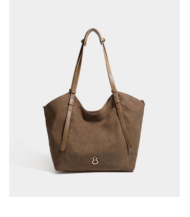 Oversized suede-finish tote shoulder bag in caramel brown with slim leather-look straps and gold-tone logo hardware, detail