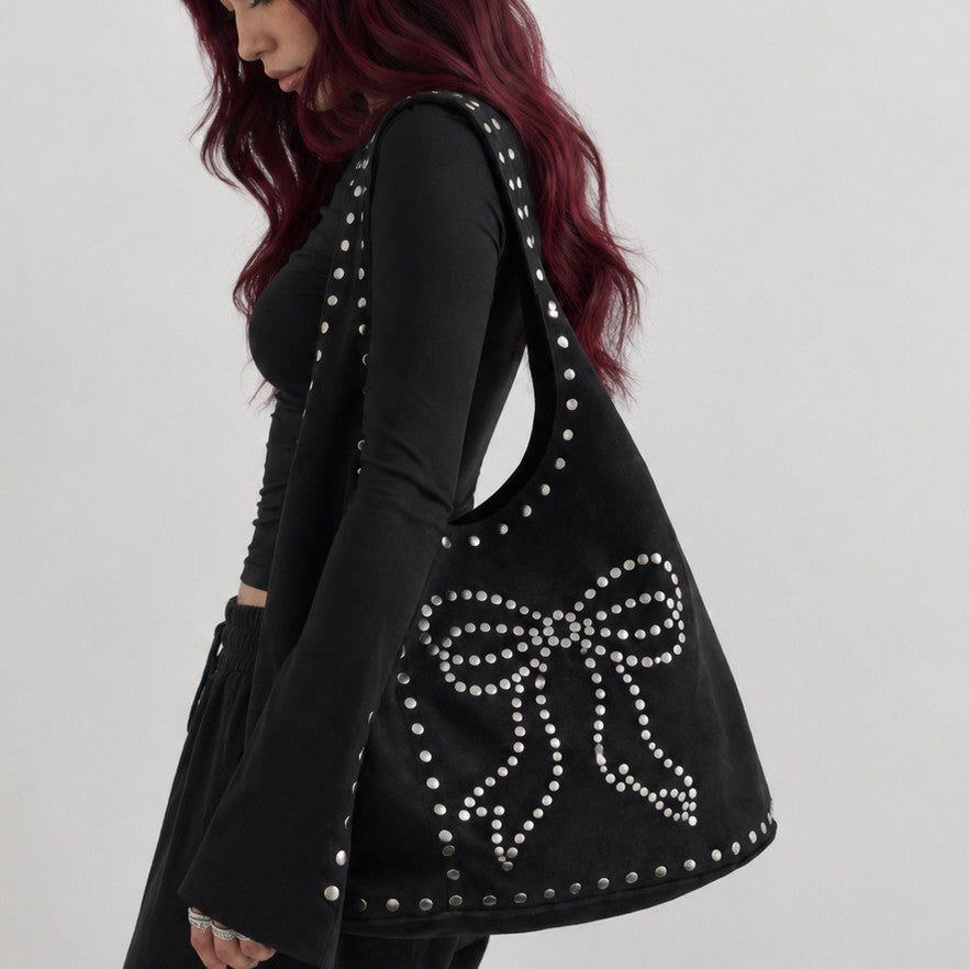 Oversized black suede-look hobo shoulder bag with silver dome studs and a large studded bow motif on the front panel, front