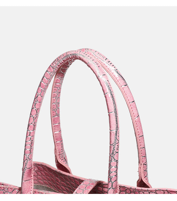 Blush pink glossy crocodile-embossed structured tote bag with studded trim, silver-tone hardware, double top handles, and