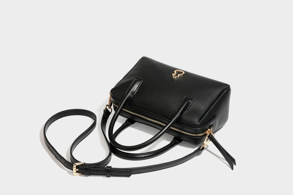 Small structured pillow satchel bag with pebbled leather-look finish, dual rolled top handles, gold-tone gourd emblem, and