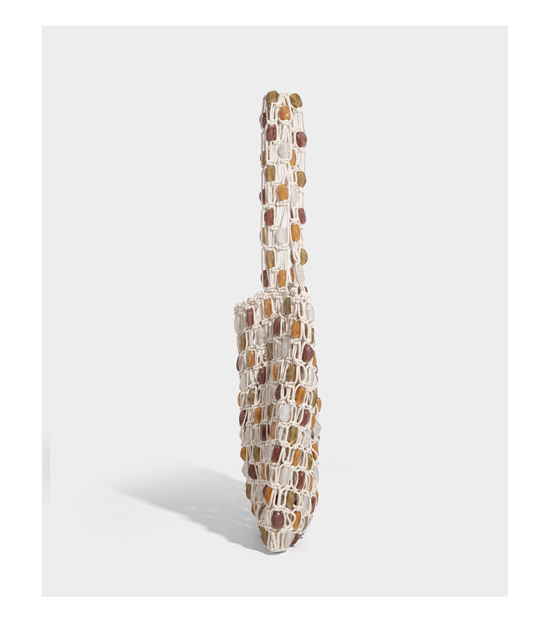 Cream macramé open-weave tote bag with multicolor amber olive and translucent bead accents and woven shoulder straps, detail