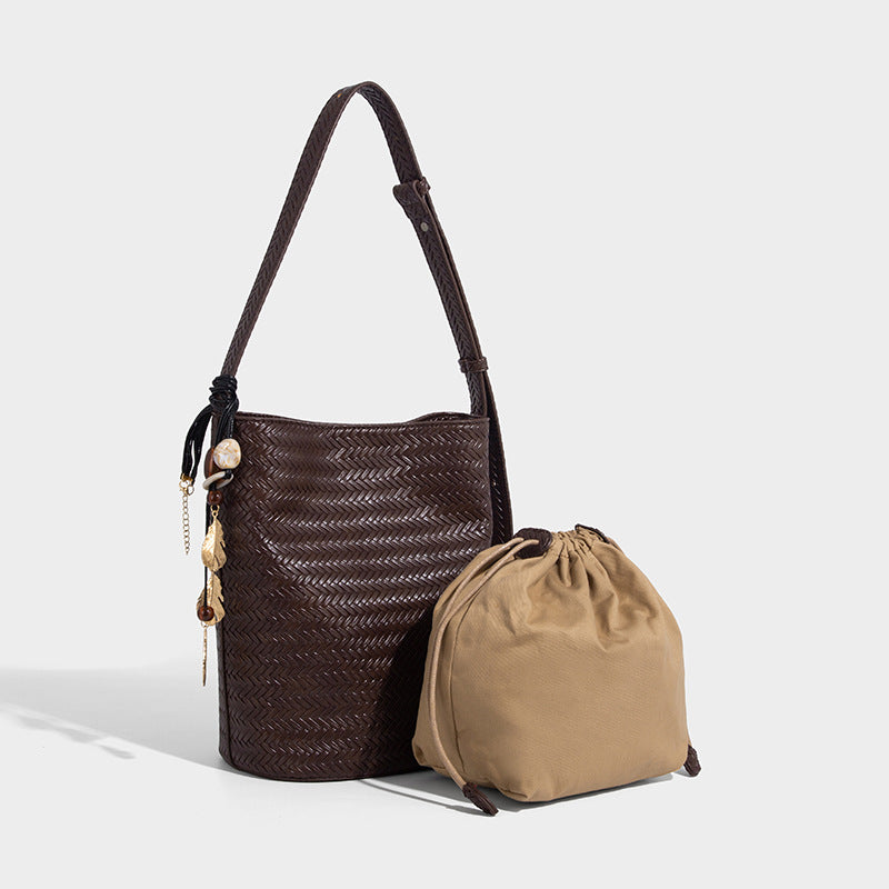 Chevron woven leather-look bucket bag with adjustable shoulder strap and gold charm pendant, front view
