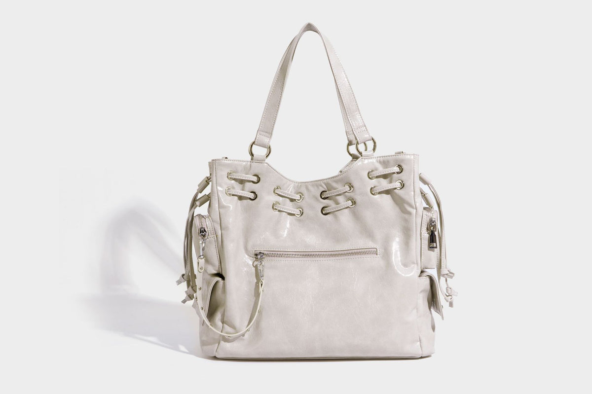Glossy crinkled leather-look tote bag with silver grommet lace-up front detail, dual top handles, and detachable shoulder