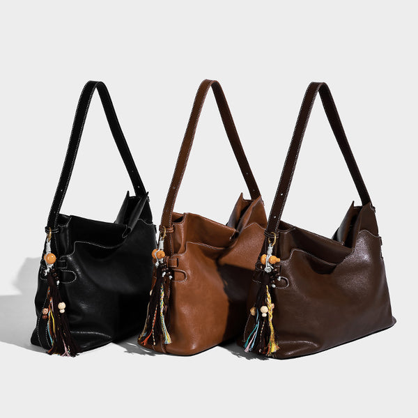 Large slouchy leather-look hobo tote bag with open top, adjustable shoulder strap, and colorful tassel bead charm, detail