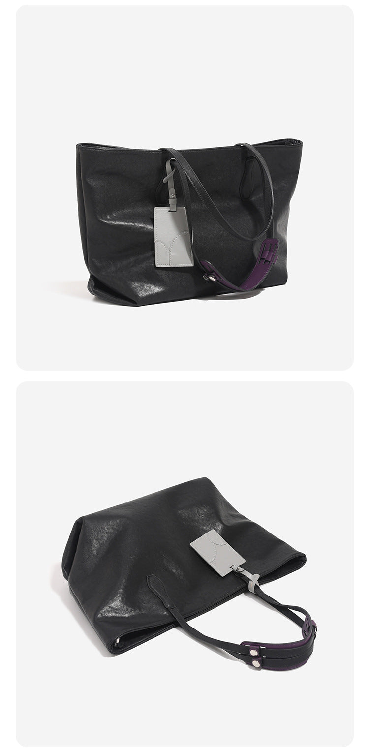 Oversized slouchy leather-look tote bag with long shoulder straps, contrast grey hanging tag, and silver-tone hardware