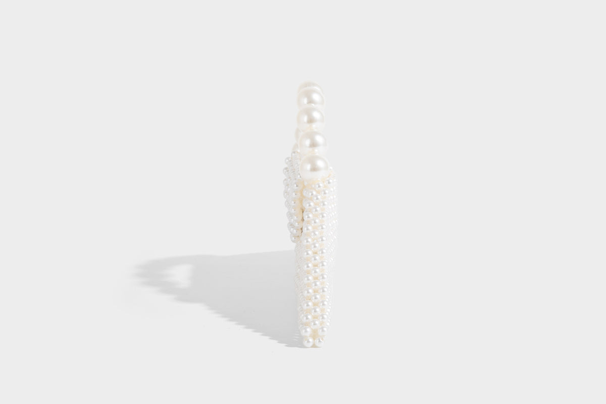 Small structured triangle clutch bag covered in glossy pearl beads with an arched pearl top handle and silver snap closure