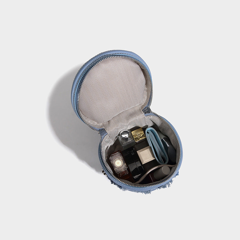 Mini cylindrical barrel bucket bag in denim patchwork with frayed edges, smooth leather-look trim, zip-around top closure