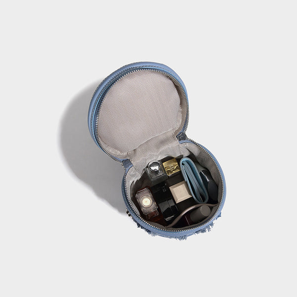 Mini cylindrical barrel bucket bag in denim patchwork with frayed edges, smooth leather-look trim, zip-around top closure