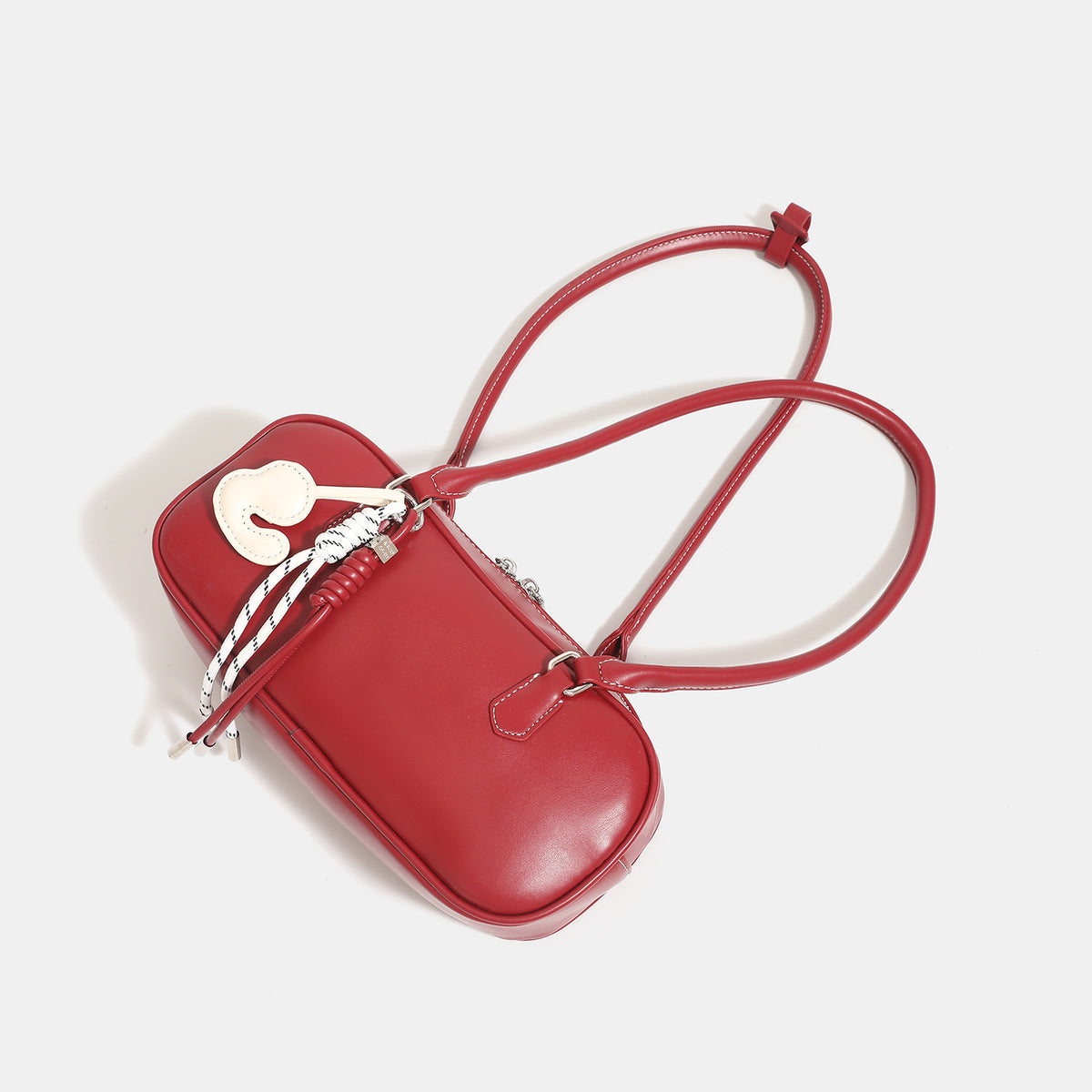 Compact rounded baguette shoulder bag with smooth leather-look finish, slim double straps, silver-tone zipper hardware, and