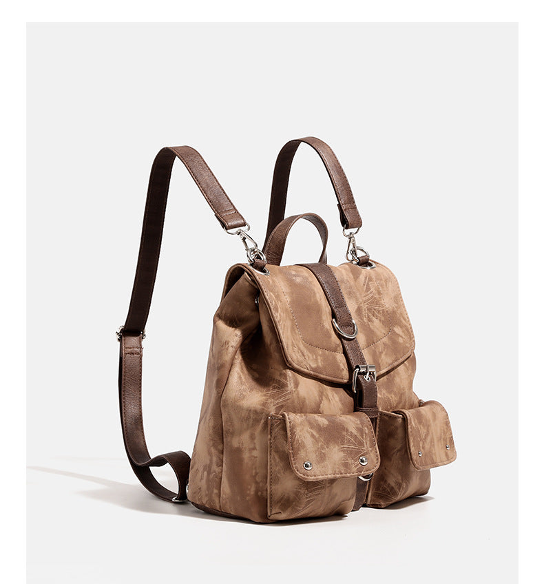Compact distressed leather-look tan-brown backpack handbag with flap-and-buckle closure, two front patch pockets, top handle