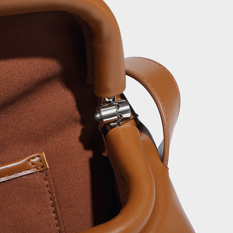 Compact structured baguette shoulder bag with smooth leather-look finish, zip top, and adjustable silver-buckle strap, detail
