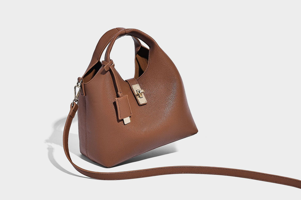 Structured pebbled-texture bucket bag with arched top handles, gold-tone turn-lock closure, and detachable shoulder strap