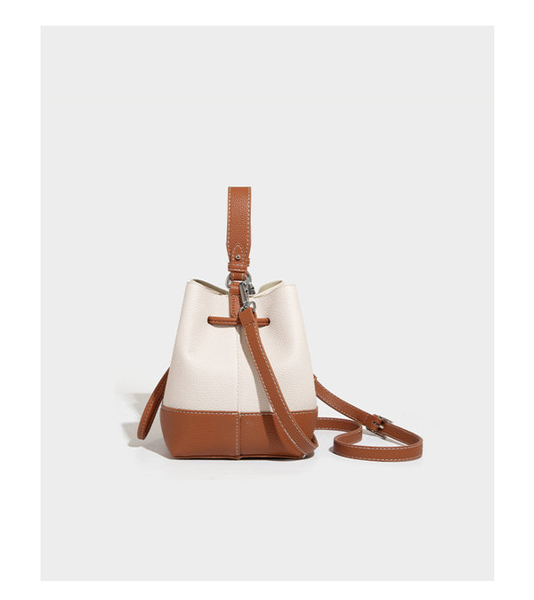 Small two-tone pebbled drawstring bucket bag with tan contrast base, metal toggle hardware, short top handle, and detachable