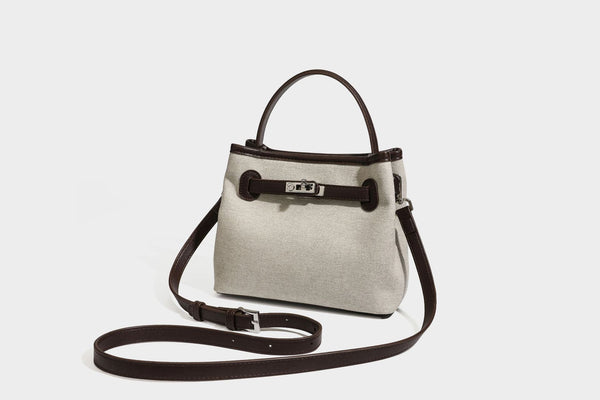 Small structured beige canvas top-handle bag with dark brown leather-look trim, silver turn-lock hardware, and detachable