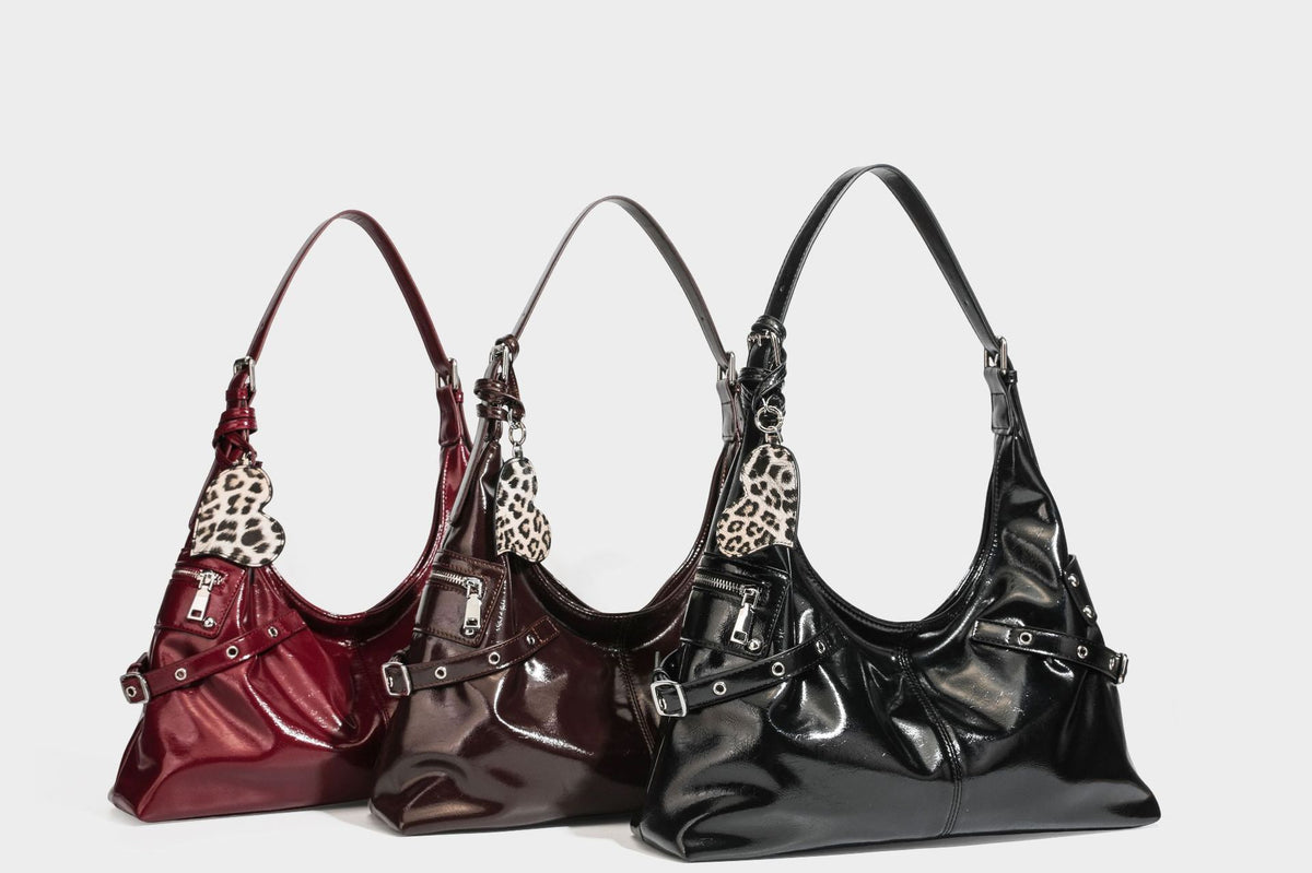 Glänzende dunkelbraune, lässig geschnittene Hobo-Schultertasche mit Riemendetail mit silberfarbenen Ösen, Reißverschlussfach auf der Vorderseite und Herz mit Leopardenmuster