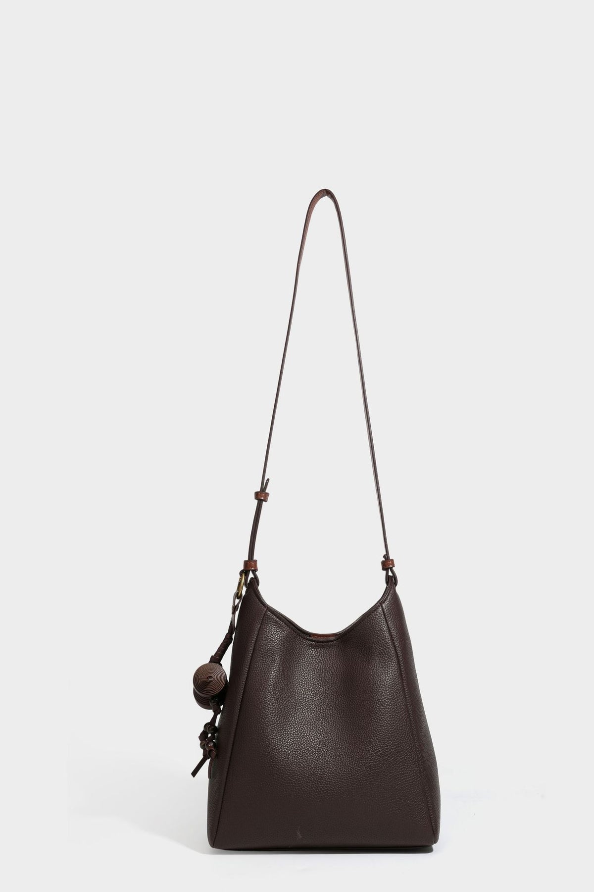 Hobo-Schultertasche in dunklem Espresso mit genarbter Oberfläche, warmen cognacfarbenen Details, verstellbarem schmalem Riemen, goldfarbenen Ringbeschlägen und geknotetem