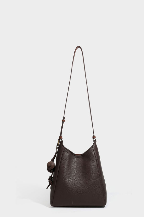 Hobo-Schultertasche in dunklem Espresso mit genarbter Oberfläche, warmen cognacfarbenen Details, verstellbarem schmalem Riemen, goldfarbenen Ringbeschlägen und geknotetem