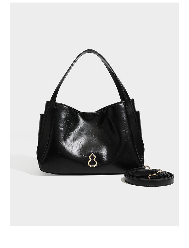 Black glossy crinkled leather-look convertible shoulder tote bag with gold gourd-shaped emblem hardware and detachable