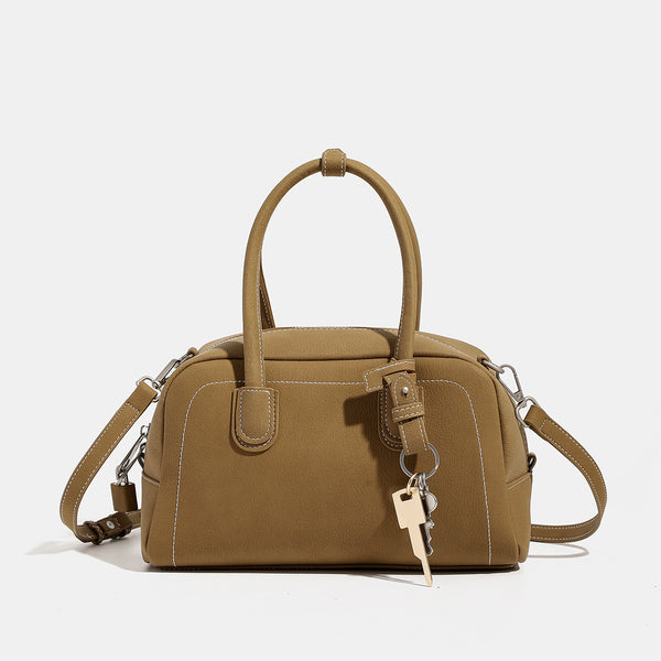 Kompakte, strukturierte Henkeltasche mit matter genarbter Oberfläche, geknoteten Doppelgriffen, goldenem Schlüsselanhänger und abnehmbarem, Detailansicht