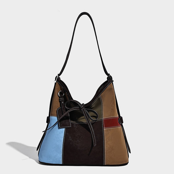Patchwork bucket tote shoulder bag with tan, dark brown, olive, red, and sky blue color-block panels, white contrast, front