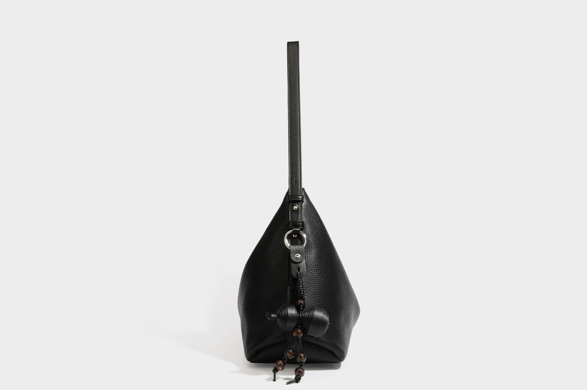 Slouchy hobo shoulder bag with pebbled leather-look finish, zip-top closure, gold-tone hardware, and hanging bead charm
