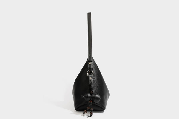 Slouchy hobo shoulder bag with pebbled leather-look finish, zip-top closure, gold-tone hardware, and hanging bead charm