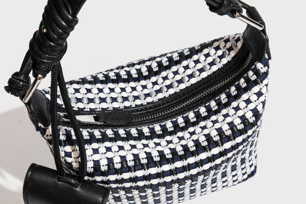 Small crescent shoulder bag in black-and-white woven textile with smooth black leather-look trim, zip-top closure, knotted