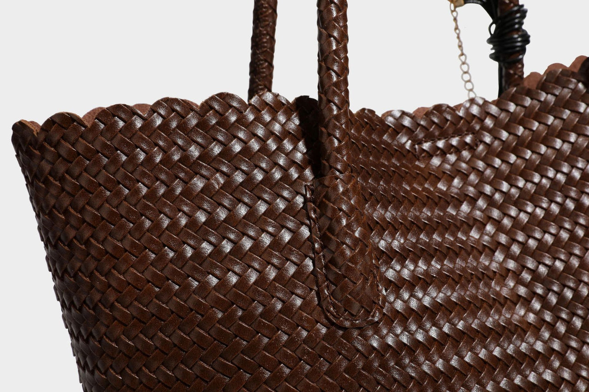 Large open-top woven leather-look tote bag in dark brown with scalloped edge, braided double shoulder straps, and decorative