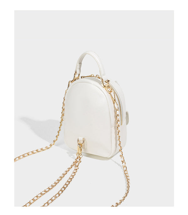 Structured mini backpack handbag with butterfly embroidery, gold-tone chain strap, and turn-lock front flap pocket, detail