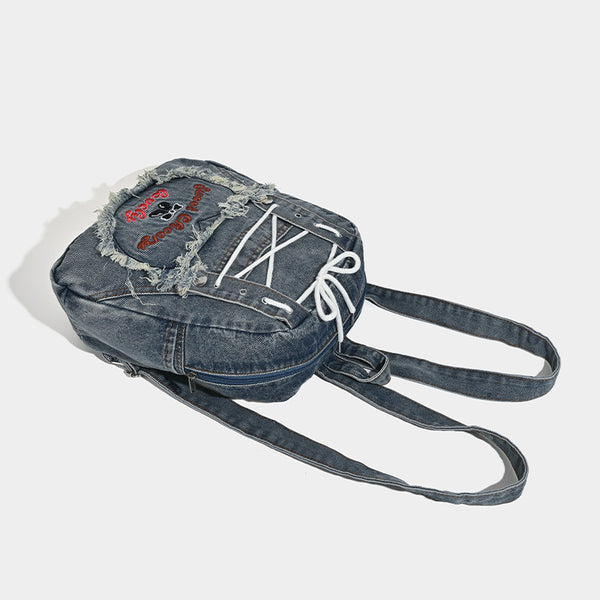 Rucksack aus gewaschenem blauem Denim mit weißer Schnürung auf der Vorderseite, ausgefranstem, herzförmigem besticktem Außenfach und Reißverschluss oben