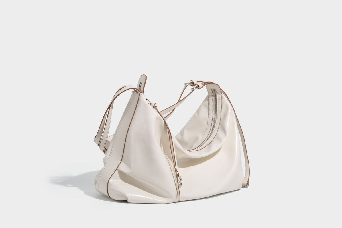 Glossy black slouchy hobo shoulder bag with zip closure, silver-tone ring hardware, and adjustable crossbody strap, detail