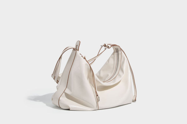Glossy black slouchy hobo shoulder bag with zip closure, silver-tone ring hardware, and adjustable crossbody strap, detail