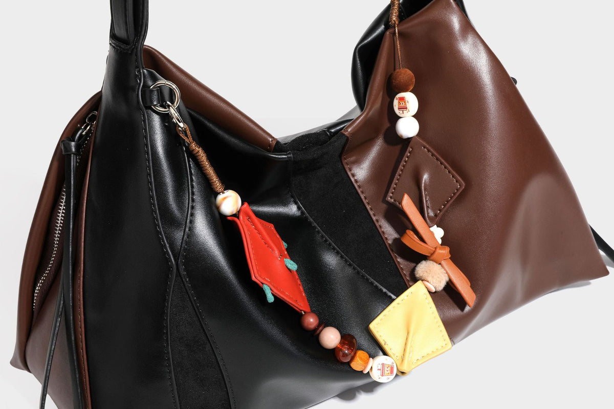 Two-tone black and brown leather-look slouchy shoulder bag with beaded tassel charm and silver-tone hardware, detail view 24