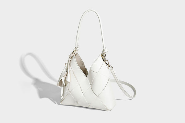 Compact bucket shoulder bag with black-and-white diamond patchwork panels, knotted top handle, gold-tone hardware, and