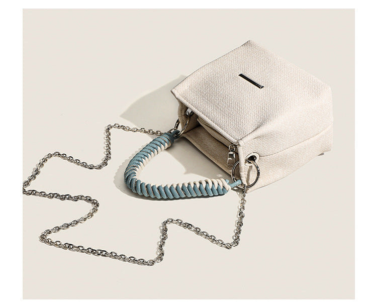 Small structured trapezoid mini bag with coiled rope top handle and silver-tone chain strap in textured fabric, detail view