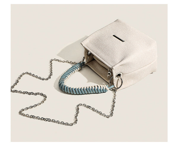Small structured trapezoid mini bag with coiled rope top handle and silver-tone chain strap in textured fabric, detail view