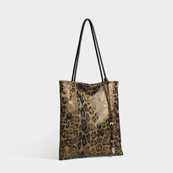 Large leopard print shoulder tote bag in tan and brown with slim dark straps and dangling beaded charm hardware, front view