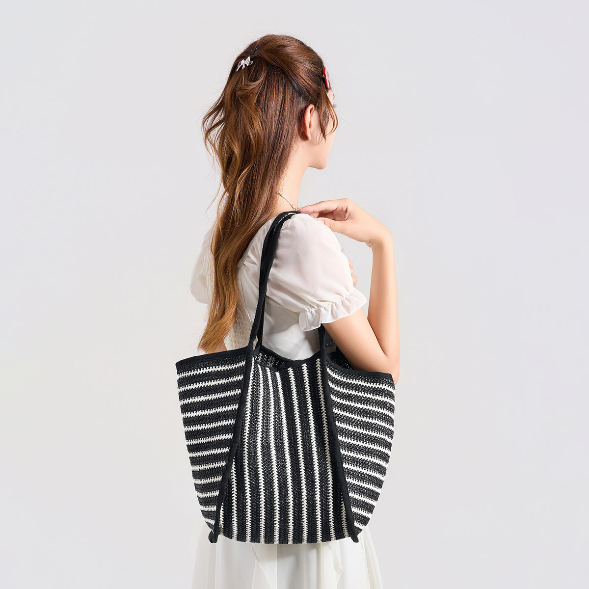 Large black-and-white striped woven tote bag with open top and long shoulder straps, front view