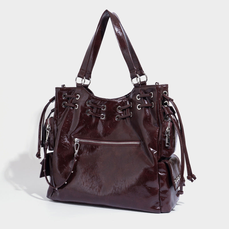 Glossy crinkled leather-look tote bag with silver grommet lace-up front detail, dual top handles, and detachable shoulder