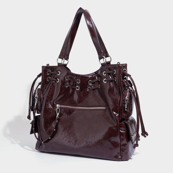 Glossy crinkled leather-look tote bag with silver grommet lace-up front detail, dual top handles, and detachable shoulder