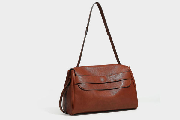 Strukturierte rechteckige dunkelbraune Schultertasche in Lederoptik mit Klappe, mehrlagigem Detail auf der Vorderseite und langem verstellbarem Riemen, Detailansicht