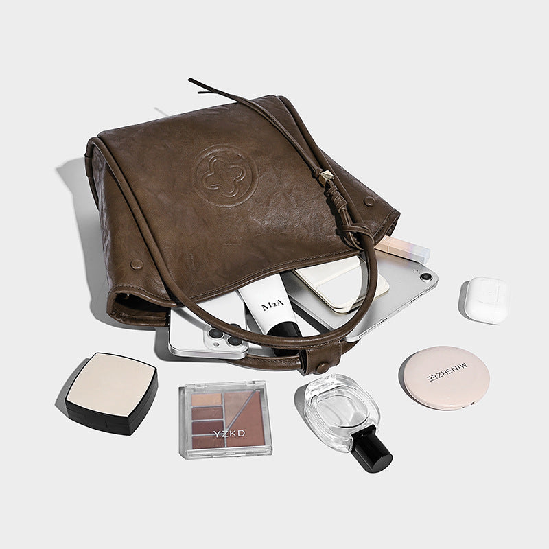 Glänzende Tote-Bag in geknautschter Lederoptik mit geprägtem Rundemblem, Quastenverschluss, zwei Tragegriffen und abnehmbarem