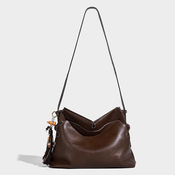 Large slouchy leather-look hobo tote bag with open top, adjustable shoulder strap, and colorful tassel bead charm, detail