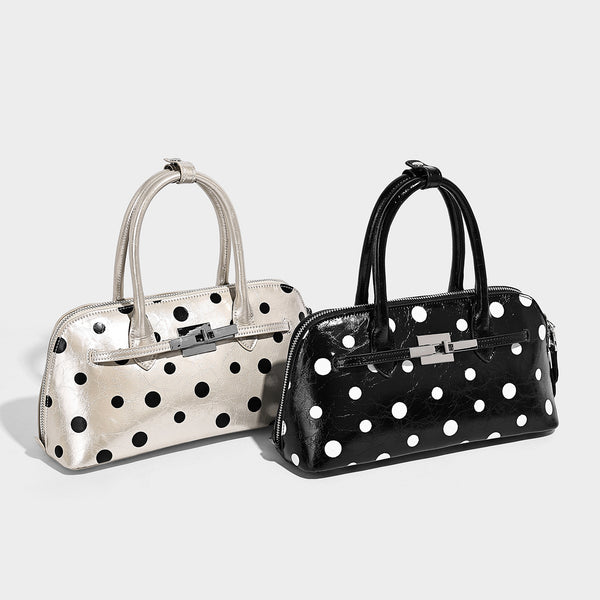 Glossy structured polka-dot satchel bag with dual top handles, silver turn-lock hardware, and detachable shoulder strap