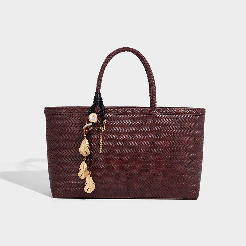 Structured woven-texture tote bag with brown braided top handles, decorative tassel charm, and detachable shoulder strap