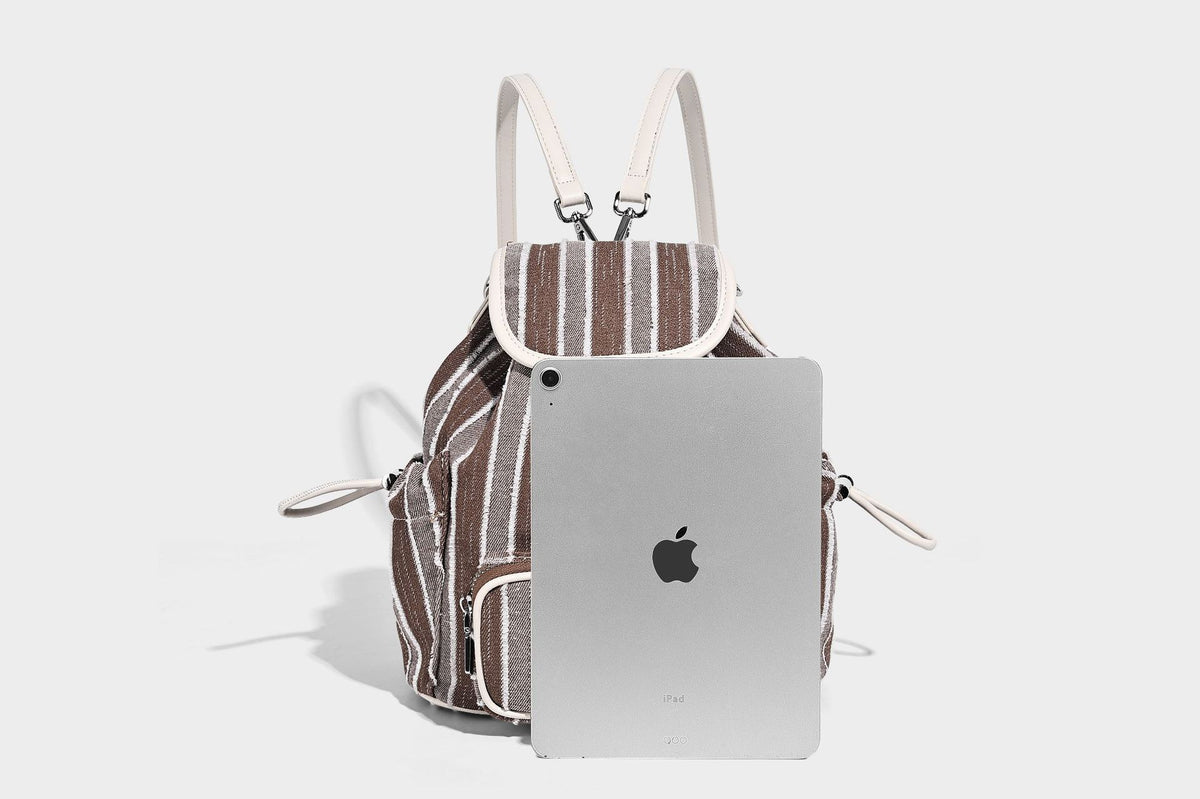 Weicher Rucksack aus gewebtem Material mit vertikalen Streifen, Überschlag, Kordelzug, vorderer Reißverschlusstasche, weißen Besätzen und Trägern in Lederoptik, Detailansicht