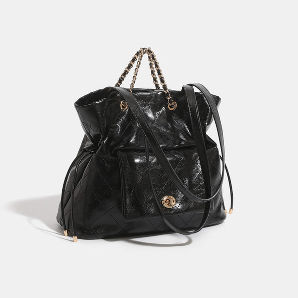 Black glossy diamond-quilted bucket tote bag with gold-tone chain accent, turn-lock front flap pocket, drawstring side ties